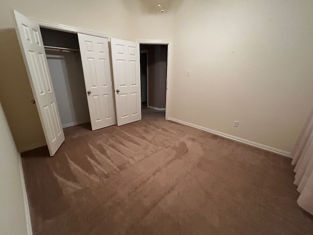 unfurnished bedroom featuring a high ceiling, dark colored carpet, and a closet