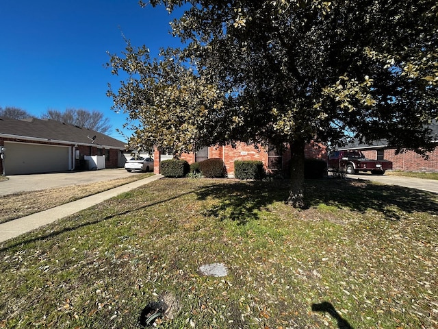 view of property hidden behind natural elements with a garage and a front yard