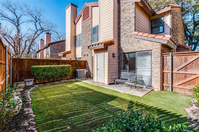 rear view of property featuring central AC, a lawn, and a patio