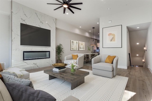 living room featuring a ceiling fan, wood finished floors, recessed lighting, and a fireplace