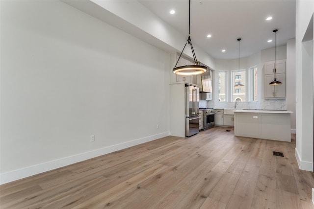 kitchen featuring baseboards, light countertops, premium appliances, recessed lighting, and light wood-style floors