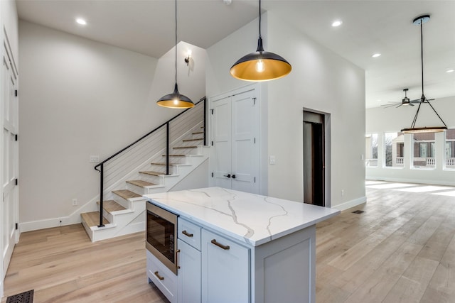 kitchen with light wood-type flooring, visible vents, pendant lighting, stainless steel microwave, and a kitchen island