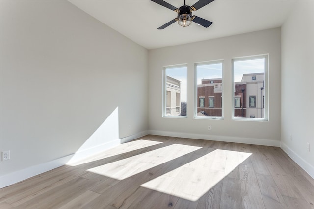 empty room with baseboards, a ceiling fan, and light wood finished floors