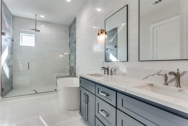 bathroom featuring visible vents, a sink, tile walls, a shower stall, and double vanity