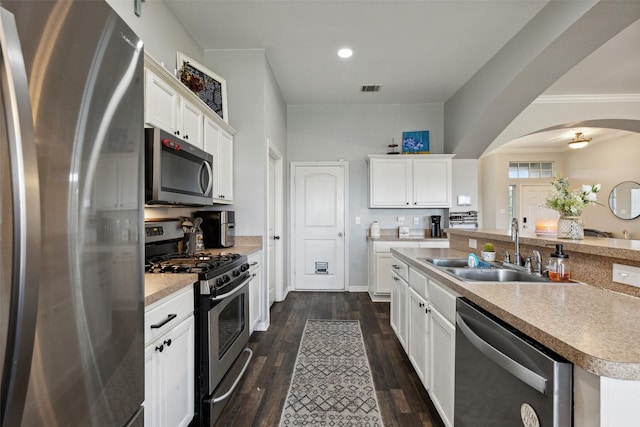 kitchen with stainless steel appliances, white cabinetry, sink, and a center island with sink