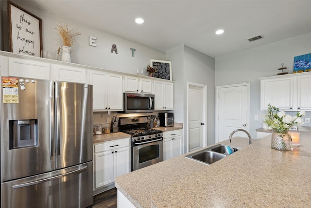 kitchen with stainless steel appliances, light stone countertops, sink, and white cabinets