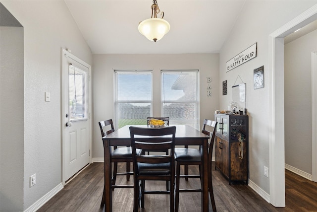 dining area with dark wood-type flooring and vaulted ceiling