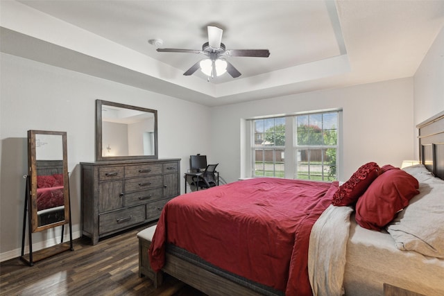 bedroom with ceiling fan, dark hardwood / wood-style floors, and a raised ceiling