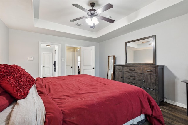 bedroom featuring dark wood-type flooring, a raised ceiling, and ceiling fan