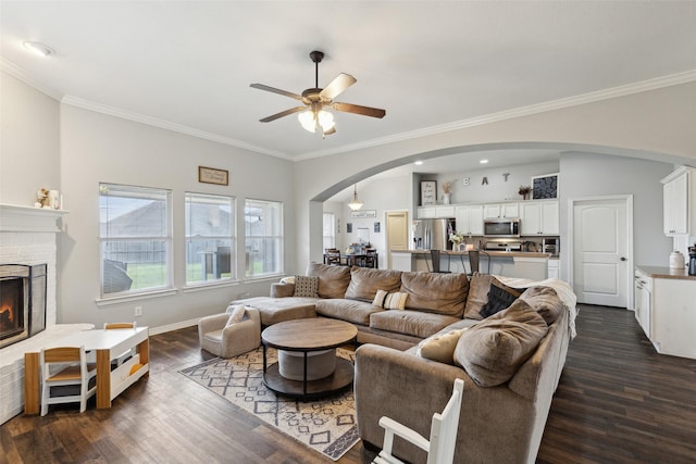 living room featuring crown molding, dark hardwood / wood-style floors, ceiling fan, and a fireplace