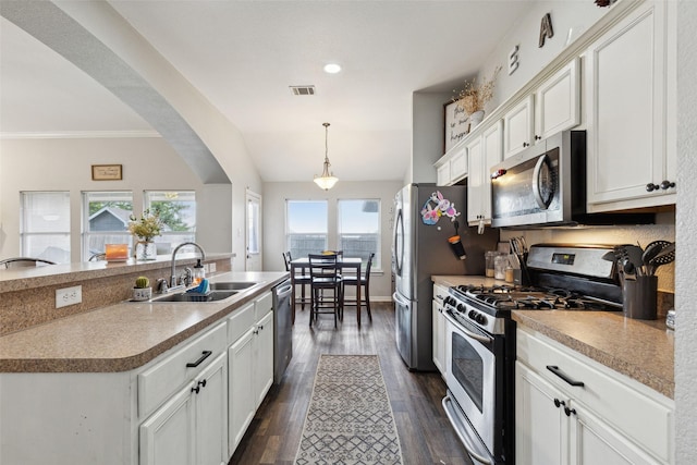 kitchen with sink, a kitchen island with sink, stainless steel appliances, white cabinets, and decorative light fixtures