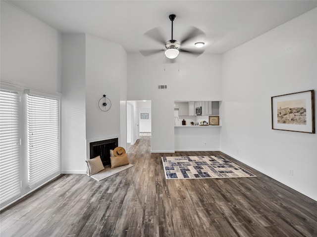 unfurnished living room featuring a high ceiling, wood-type flooring, and ceiling fan