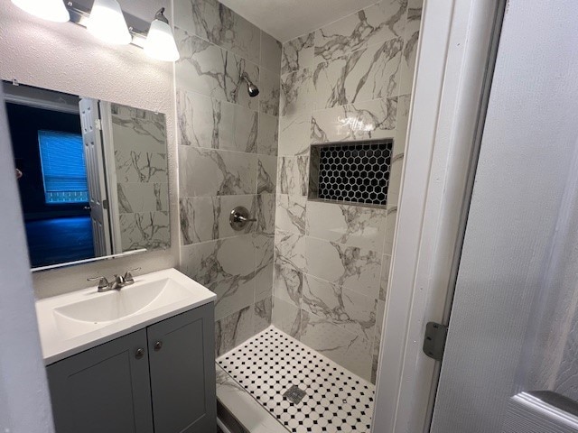 bathroom with vanity and a tile shower