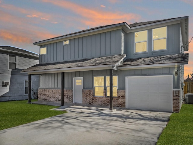 view of front of home featuring cooling unit, a garage, and a yard