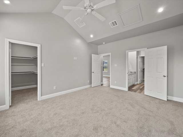 unfurnished bedroom with lofted ceiling, ceiling fan, connected bathroom, a spacious closet, and light colored carpet