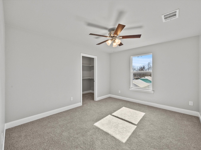 unfurnished bedroom featuring ceiling fan, a spacious closet, carpet floors, and a closet