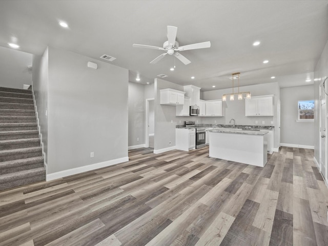 kitchen featuring white cabinetry, hanging light fixtures, light hardwood / wood-style flooring, a kitchen island, and stainless steel appliances