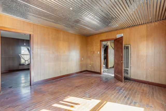 empty room featuring hardwood / wood-style floors, wooden ceiling, and wood walls