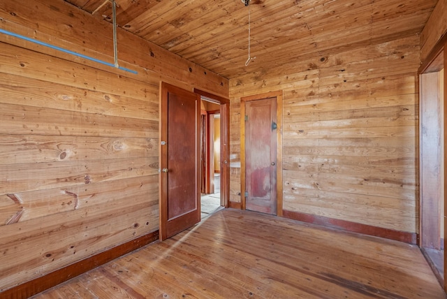 empty room with wood ceiling, wooden walls, and hardwood / wood-style flooring