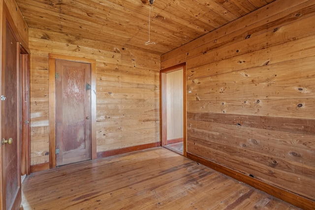 unfurnished room featuring hardwood / wood-style flooring, wooden walls, and wooden ceiling