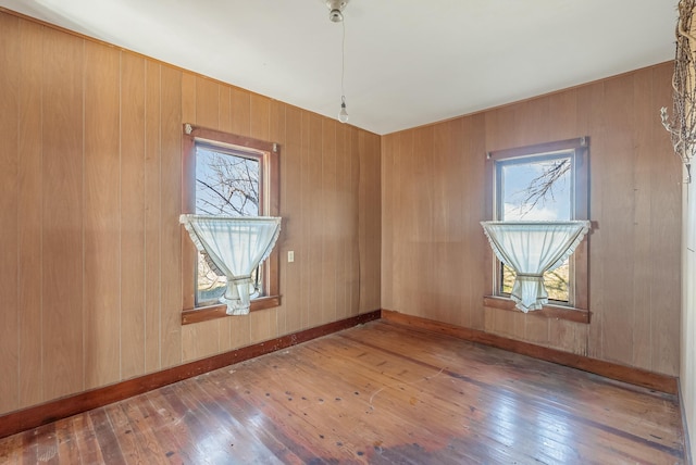 spare room with dark hardwood / wood-style flooring and wood walls