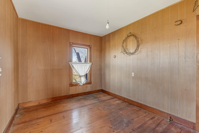 unfurnished room featuring hardwood / wood-style flooring and wood walls