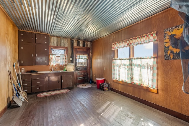 kitchen with dark brown cabinets, light wood-type flooring, and wood walls