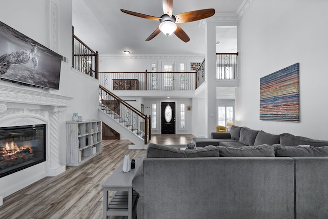 living room featuring crown molding, hardwood / wood-style floors, a towering ceiling, and ceiling fan