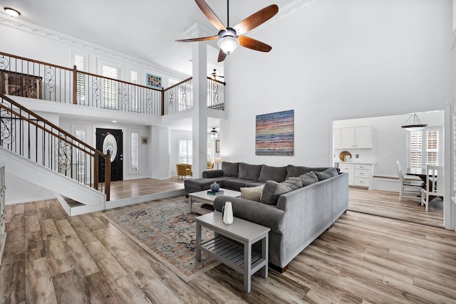 living room with ceiling fan, light wood-type flooring, a healthy amount of sunlight, and a high ceiling