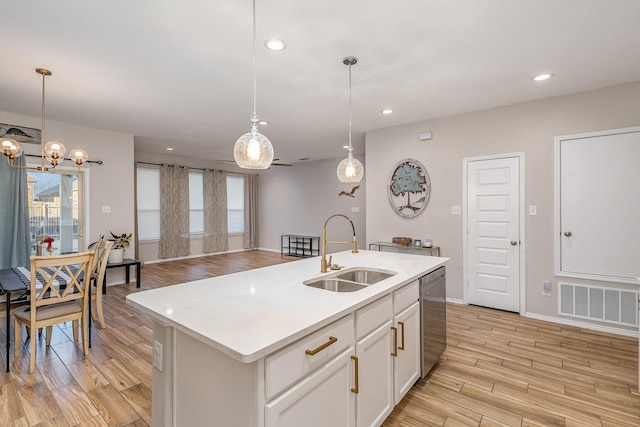 kitchen with sink, hanging light fixtures, dishwasher, and a center island with sink