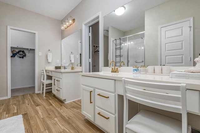 bathroom with wood-type flooring, vanity, and a shower with shower door