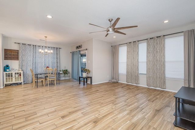 interior space with ceiling fan with notable chandelier and light wood-type flooring