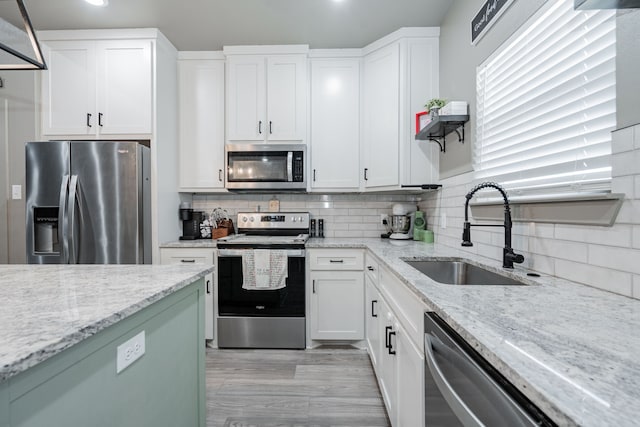 kitchen featuring tasteful backsplash, white cabinetry, appliances with stainless steel finishes, and sink