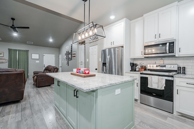 kitchen with vaulted ceiling, a kitchen island, appliances with stainless steel finishes, white cabinetry, and backsplash