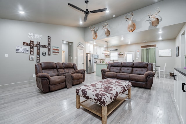 living room with ceiling fan, lofted ceiling, and light hardwood / wood-style flooring