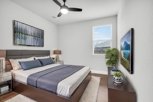 bedroom featuring visible vents, a ceiling fan, baseboards, and wood finished floors