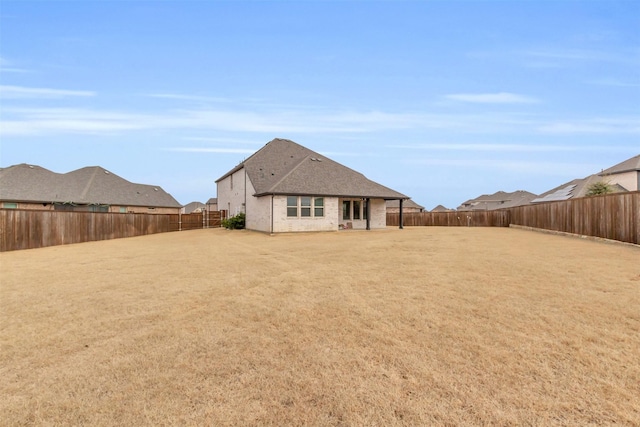 rear view of house with a lawn, a fenced backyard, and brick siding