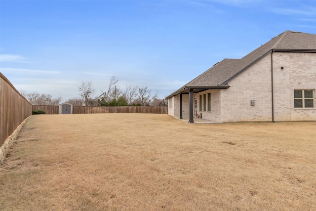 view of yard featuring a patio area, a storage unit, a fenced backyard, and an outdoor structure