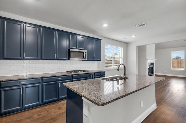 kitchen with blue cabinets, appliances with stainless steel finishes, sink, and a center island with sink