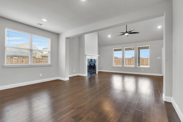 unfurnished living room with ceiling fan, plenty of natural light, dark hardwood / wood-style floors, and a tile fireplace