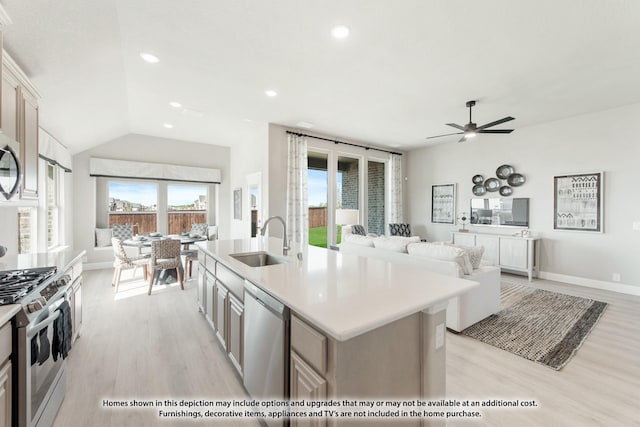 kitchen with sink, a center island with sink, light hardwood / wood-style flooring, appliances with stainless steel finishes, and ceiling fan