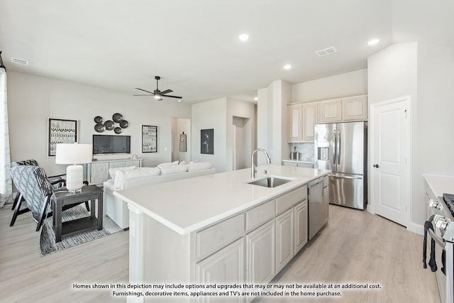 kitchen featuring appliances with stainless steel finishes, sink, ceiling fan, light hardwood / wood-style floors, and a center island with sink