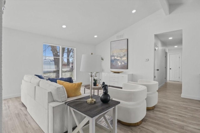 living room featuring vaulted ceiling with beams and light hardwood / wood-style flooring