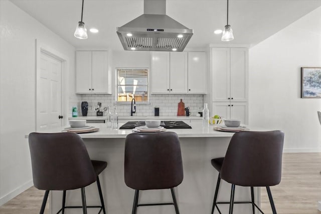 kitchen featuring white cabinetry, island exhaust hood, hanging light fixtures, and decorative backsplash