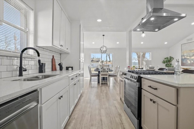 kitchen with island range hood, white cabinetry, sink, light hardwood / wood-style floors, and stainless steel appliances