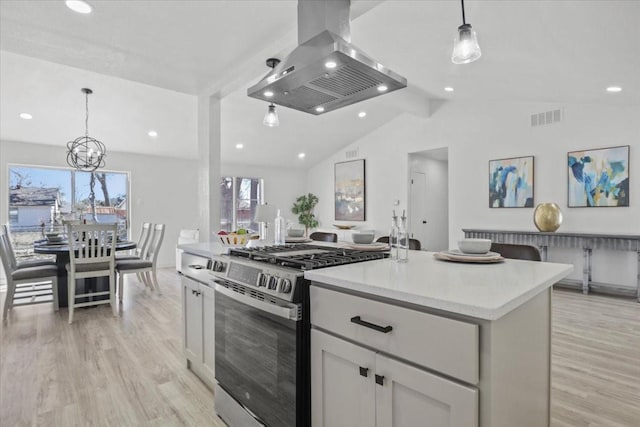 kitchen featuring island exhaust hood, decorative light fixtures, white cabinets, and stainless steel gas stove