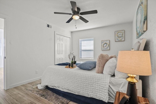 bedroom with light hardwood / wood-style flooring, ceiling fan, and a closet