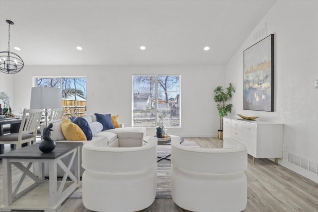 living room with an inviting chandelier and light wood-type flooring