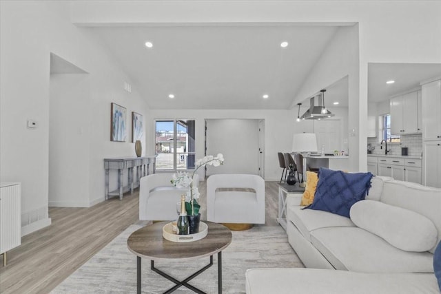 living room with beamed ceiling, radiator, high vaulted ceiling, and light hardwood / wood-style flooring