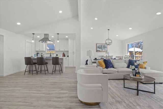 living room featuring high vaulted ceiling, a chandelier, and light hardwood / wood-style floors